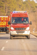 Red fire truck moving on a rural road, fire brigade exercise on the Hermann Hesse Railway,