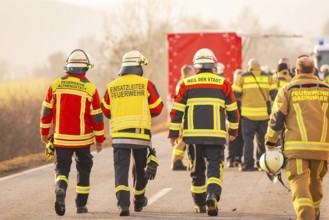 Fire team walking on the road, red vehicle protection in the background, fire department exercise