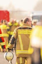 Firefighter with helmet in hand, blurred background activity, fire brigade exercise on the Hermann