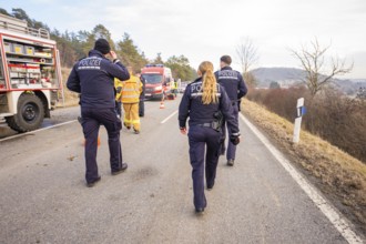 Officials are walking on a street towards an operation. Ambulances and fire engines can be seen,