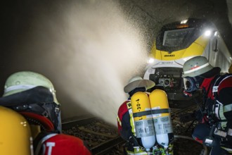 Firefighters spray a train in a tunnel with water. Respirators are used, fire department exercise