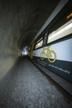 Train with bicycle graphics on the side passes through a tunnel, fire department exercise on the
