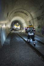 Firefighters with equipment work on rails in a tunnel, fire brigade exercise on the Hermann Hesse