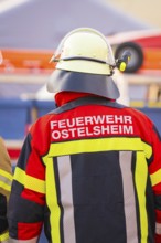Firefighter from behind wearing colorful protective clothing and helmet, fire department exercise