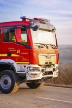 Red fire engine on a street in sunshine, fire brigade exercise on the Hermann Hesse railway,