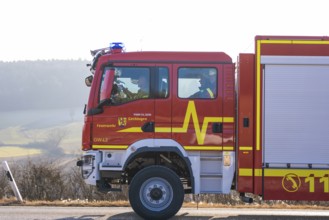 Side view of a red emergency vehicle on a wintry country road, fire department exercise on the