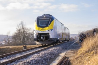 Modern train travels on tracks through rural winter landscape under clear skies, fire brigade