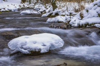 Small watercourse in winter with ice floes and mossy stones, Brühlbach below Urach Waterfall, Bad