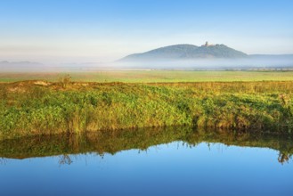 Landscape with lake in morning light, fog over the fields, the ruins of Gleichen Castle in the