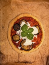 Delicious ready-made homemade pizza with eggplant and burrata on baking paper, food photography,