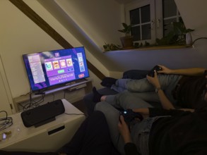 Friends sitting on the couch playing a video game on a TV with Steam Deck, video game Vampire