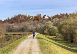 Jogger on a path along the Isar with a view of Grünwald with Bürg Grünwald, Grünwald, Bavaria,