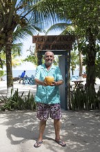 German manager, 67 years old, at Playa Blanca with a coconut, Izabal Department, Guatemala