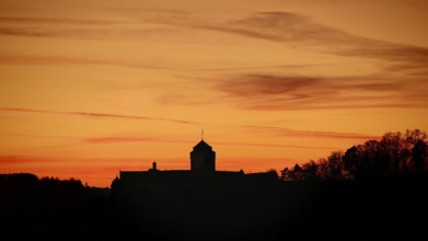 Silhouette of a castle at sunset, warm tones above the horizon, view of Rosenberg Fortress,
