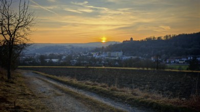 Sunset behind a small town, warm light over hills and a country road, view of Rosenberg Fortress,