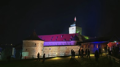 Illuminated castle at night with visitors and colorful lighting, Kronach glows, Frankenwald nature