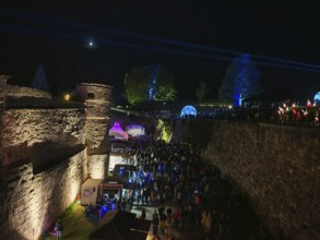 Night shot of a festival near a castle with lights and laser beams, Kronach glows, Frankenwald