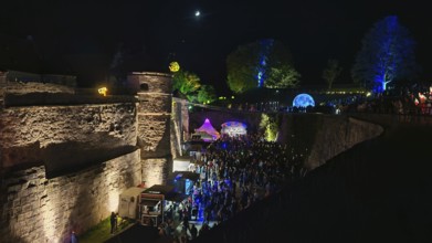 Festival atmosphere in an illuminated castle at night with many visitors, Kronach glows,