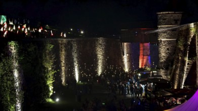 Night view of a festival with illuminated castle walls and visitors, Kronach glows, Frankenwald