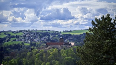View of a castle surrounded by green hills and dramatic clouds, view of Rosenberg Fortress,