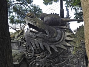 A detailed stone dragon statue surrounded by trees, with a powerful and majestic expression, Yuyuan