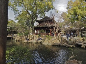Peaceful garden with pond surrounded by trees and traditional construction, Yuyuan Garden,