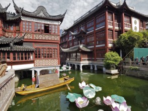 A water channel surrounded by traditional Chinese buildings and lotus flowers, Yuyuan Garden,