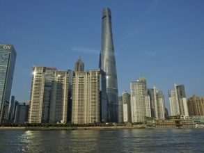 City skyline of Huangpu Jiang with tall modern buildings against blue sky on the water, Pudong,