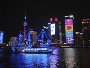 Illuminated skyline and river with an illuminated ship at night, Shanghai, China