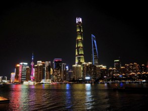 Impressive skyline of high-rise buildings, illuminated at night, stretching behind a river,