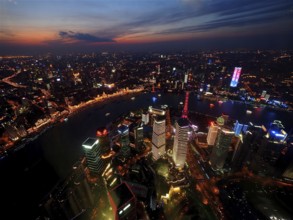 Illuminated city at dusk with view of river and skyscrapers, Shanghai, China