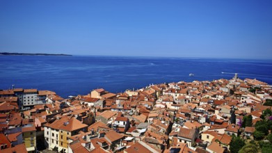 Panoramic view of a coastal town with red roofs and blue sea in the background, Piran, Slovenia