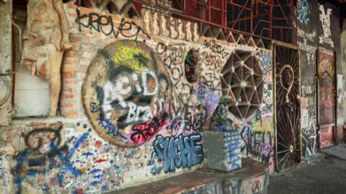 Different graffiti on a brick wall in an urban environment with a mix of cultures, Ljubljana,