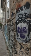 Street scene with graffiti and sprayed face on a weathered wall in an urban environment, Ljubljana,