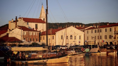 A harbor with sailboats and historic buildings in the warm evening sun, Izola, Slovenia