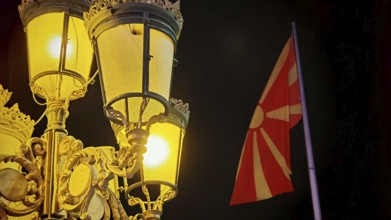 Night view of an illuminated lantern and a North Macedonia flag in the dark, Skopje, North