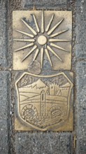Metal relief with sun symbol and historical depiction on a stone surface, Skopje, North Macedonia
