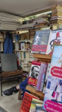 Bookshelves in an outdoor bookstore with various books, Mein Kampf, and an empty chair, Pristina,