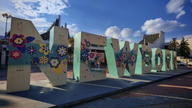 Large letter sculpture, newborn, with floral motifs against a blue sky, Pristina, Kosovo
