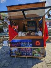 A sales stand with KLA souvenirs and flags under a blue sky, Prizren, Kosovo