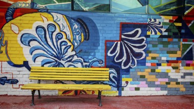 Colourful wall painting with geometric patterns and a yellow bench in the foreground, Skopje, North