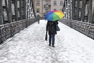 A passer-by walks across the Iron Bridge in Frankfurt am Main with an umbrella. Heavy snowfalls