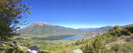 Wide view over a lake and mountains under a clear blue sky, view from above over Lake Plav,