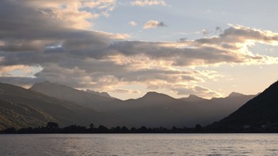 View across a lake to mountain silhouettes in warm sunset light, Plav Lake, Montenegro