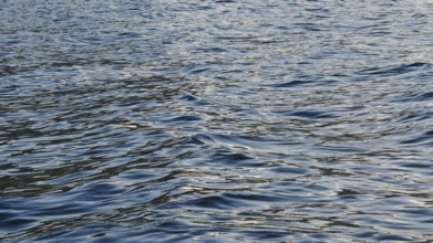 Close-up of water waves with sunlight reflections creating a vivid texture, Plav Lake, Montenegro