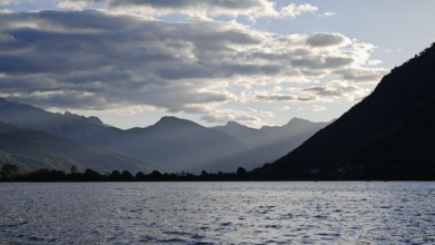 View across a lake to mountains during setting sun and cloudy sky, Plav Lake, Montenegro