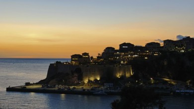 Dusk over an illuminated fortress on a coast with calm sea and warm sky, Ulcinj, Montenegro