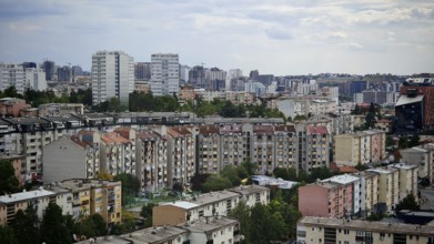 View of a city with numerous residential buildings under a slightly cloudy sky, Pristina, Kosovo