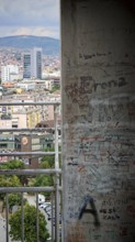 Wall with graffiti in the foreground, urban buildings and skyscrapers in the background, Pristina,