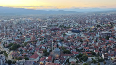 Panoramic photo of city at sunset with distinctive mosque roof and mountains, Prizren, Kosovo